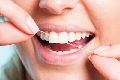 close up of woman flossing her teeth