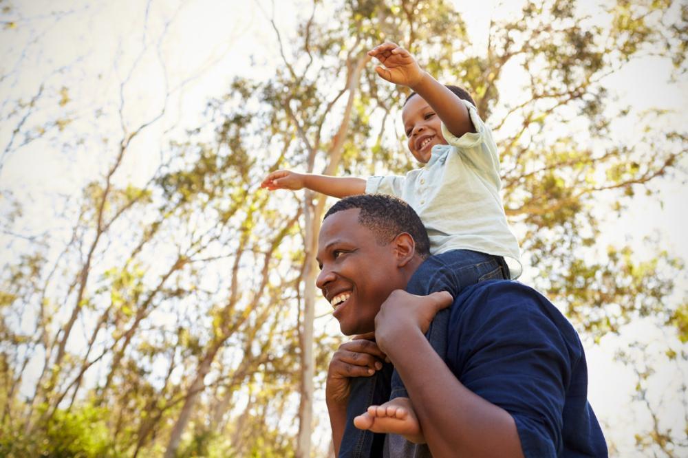 Young boy sitting on top of father's shoulders