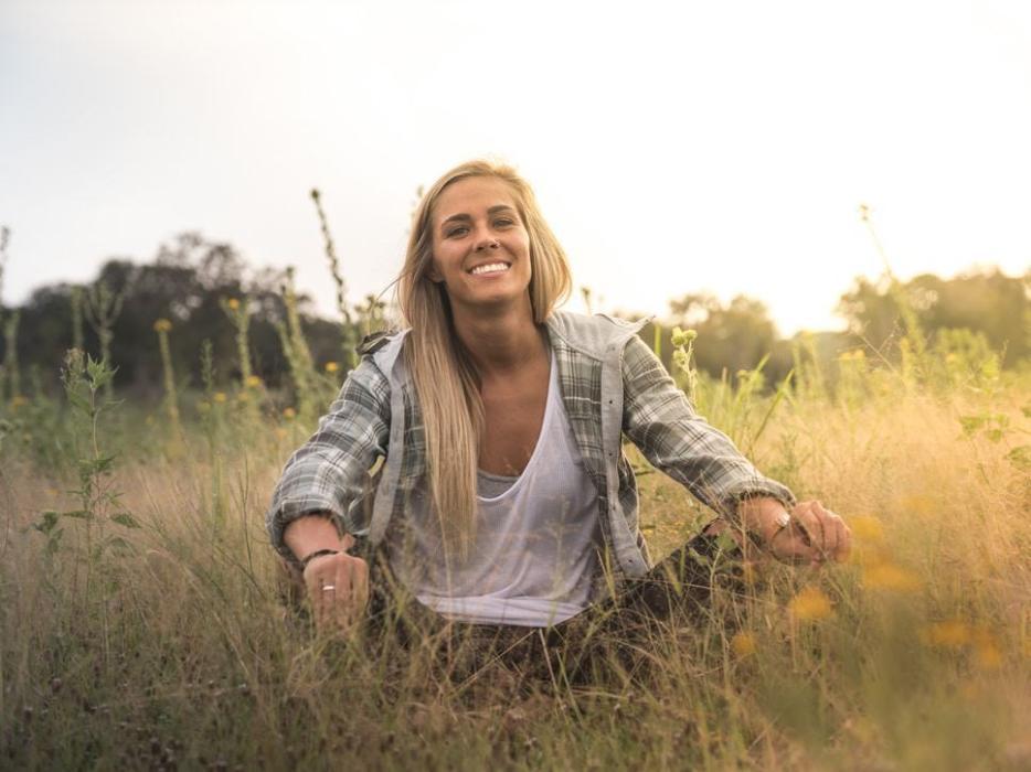 Woman smiling while sitting in field of tall grass