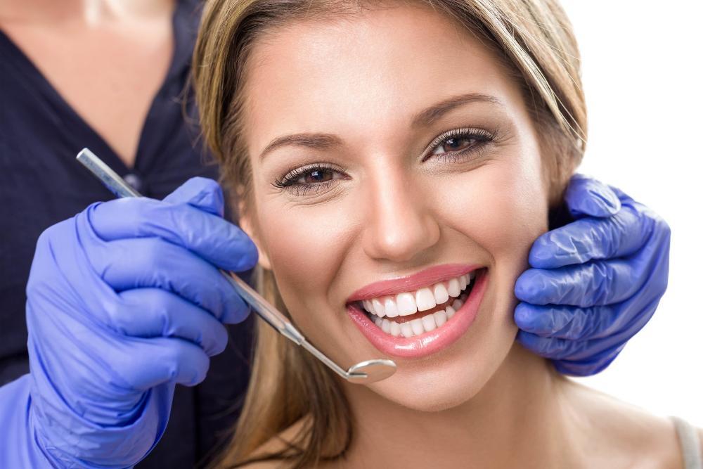 Woman smiling with dentist holding dental mirror near mouth