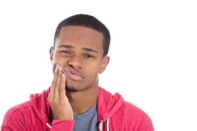 Man in red sweatshirt holding jaw from pain