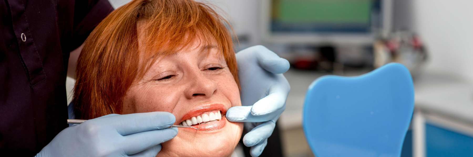woman smiling into dental mirror